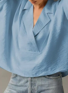Detail of light blue V-neck blouse showing textured fabric and silky sheen on a model