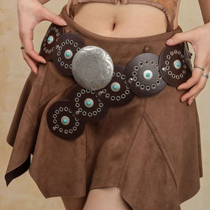 Détail d'une ceinture en daim marron avec pierres turquoise et boucle gravée