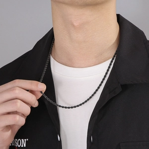 Close-up of a black twisted rope chain necklace worn by a model on grey background