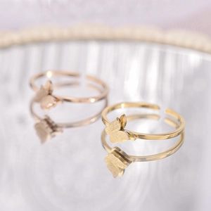 Golden and rose gold butterfly open rings with high-polish finish on reflective surface