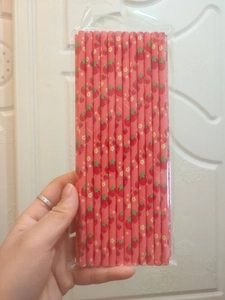 Pink paper straws with red strawberry and floral patterns in transparent packaging