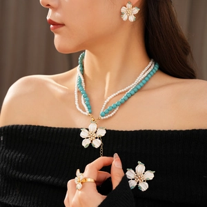 Détail d'un collier vintage en perles et turquoise avec boucles d'oreilles fleuries portées