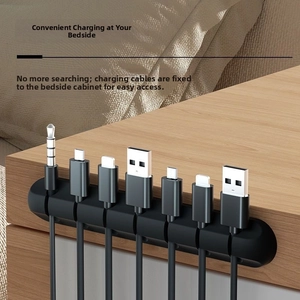 Close-up of a 7-slot black silicone cable organizer on a wooden bedside desk surface