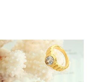 Detailed view of a golden ring with a round clear gemstone and textured band