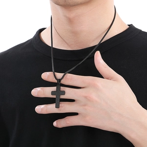 Close-up of a matte black stainless steel cross necklace with a unique cracked texture