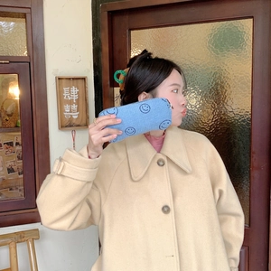 Asian model holding blue corduroy smile makeup bag in a vintage street setting