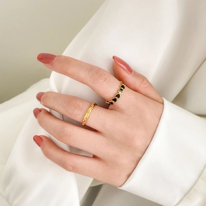 Close-up of gold heart enamel ring and thin cubic zirconia band on hand over satin