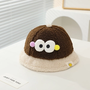 Detail of baby plush bucket hat with large cartoon eyes and colorful fuzzy ball accents