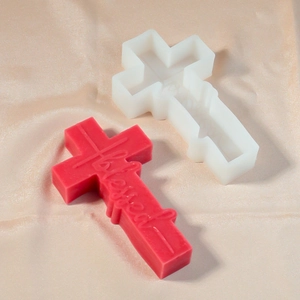 Close-up of a cross-shaped silicone mold and a red candle with blessed engraving