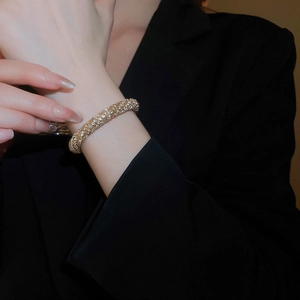 Close-up of a gold-plated twisted bangle featuring sparkling pavé crystal settings