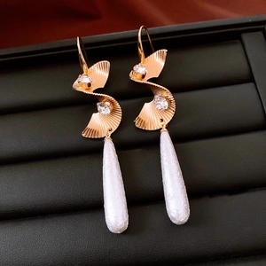 Detail of twisted gold drop earrings with pearls and crystals in a black jewelry box