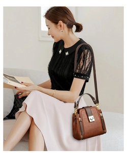 Detailed view of brown faux leather bucket bag with gold hardware and contrast stitching