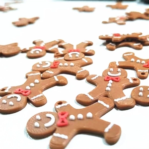 Macro detail of gingerbread man charms showing 3D drip oil texture and embossed red bows