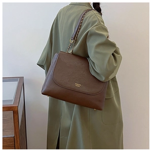 Detail of deep brown leather chain strap and flap closure on a large commuter bag