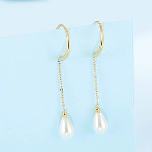 Elegant gold chain earrings with white teardrop pearl pendants on a light blue background
