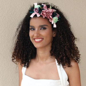 Detailed view of large fabric flowers on a wide headband worn by a model with curly hair