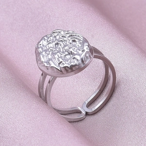 Macro detail of silver adjustable lava texture ring on pink silk fabric background