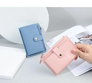 Detail of short PU leather wallets in blue and pink with zipper and snap button closure