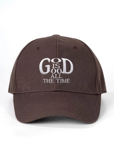 Dettaglio del ricamo bianco God Is Good su un cappellino da baseball marrone scuro