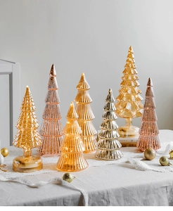 Macro shot of glass Christmas trees with LED warm light and metallic finish on white lace