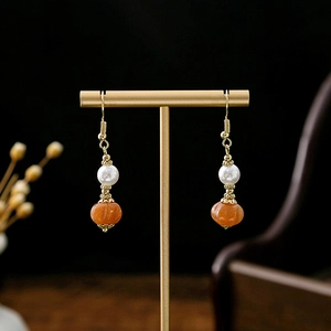 Detail of Chinese style drop earrings with white pearls and orange pumpkin beads