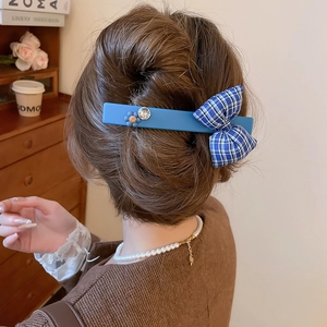 Close-up of blue floral bow hair clip with rhinestone and smiley face on hairstyle