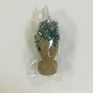 Close-up of mini snow-flocked Christmas tree with a burlap base in clear packaging