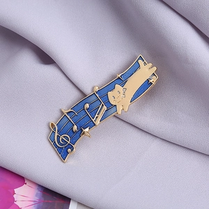Blue enamel cat musical note brooch pin with gold plating on purple fabric