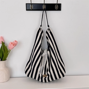 Détail du sac cabas en toile rayée avec bordure en dentelle blanche et plaque de logo