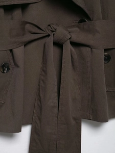 Details eines dunkelbraunen Trenchcoats mit Bindegürtel, Harzknöpfen und Doppelsteppung