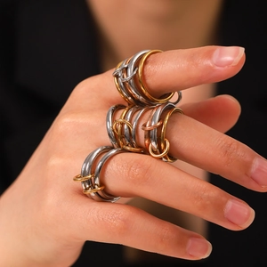 Close-up of interlocking tricolor stainless steel rings worn on finger in stacked style