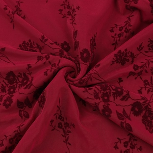 Gros plan de flocage floral en velours rouge foncé sur tissu mesh transparent et drapé