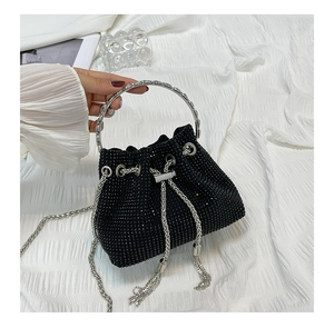Detail of a black mini bucket bag with sparkling rhinestones and silver tassels