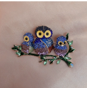 Macro shot of owl brooch with colorful crystals on a silk fabric background