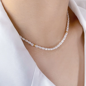 Detail of sweet freshwater pearl necklace with gold bead accents on textured shirt