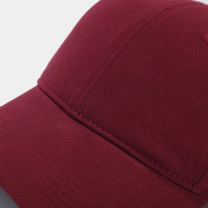 Detail of burgundy cotton twill baseball cap with reinforced stitching on the brim