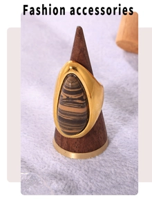Macro shot of 18K gold teardrop ring featuring natural wood grain stone on a wooden stand