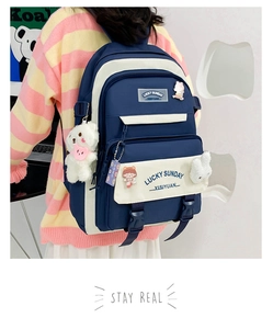 Detail of school backpack in navy blue and cream with cute bear and rabbit plush charms