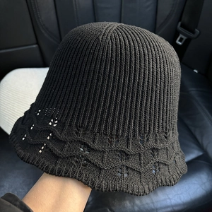 Detail of black knitted bucket hat showing intricate wavy crochet patterns on the brim
