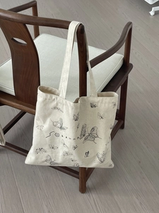 Detail of butterfly print canvas tote bag hanging on a wooden chair in natural light