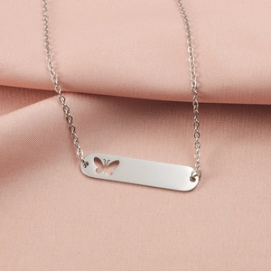 Close-up of silver rectangle pendant necklace with butterfly cutout on pink fabric