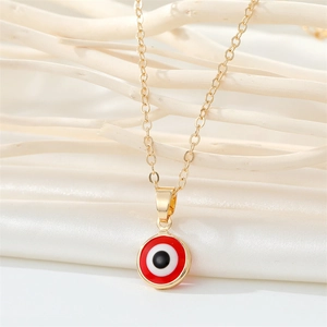 Gold stainless steel evil eye necklace with red enamel pendant on textured background