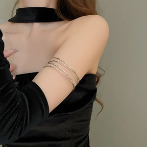 Macro detail of layered gold armlet wrap around upper arm on black velvet sleeve