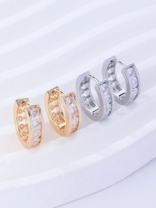 Macro shot of gold and silver huggie earrings with cubic zirconia pavé on white stand