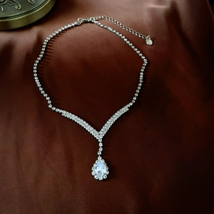 Detailed close-up of water drop rhinestone pendant necklace with V-shape silver chain