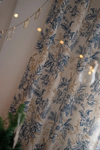 Detailed view of floral curtains with blue and gold patterns and lace trim in warm light