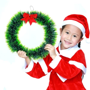 Detail of a green Christmas wreath with a red bow worn by a child on a white background