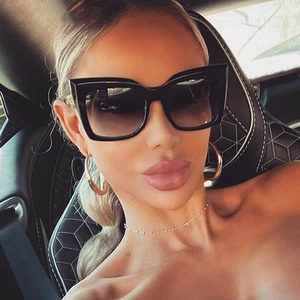 Fashionable oversized cat eye sunglasses with thick black frames and dark gradient lenses