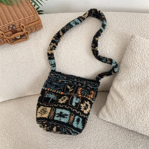Sac bandoulière en peluche avec motifs géométriques bleu et orange sur canapé