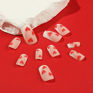 Valentine matte press-on nails with white French tips and red hearts on pink base